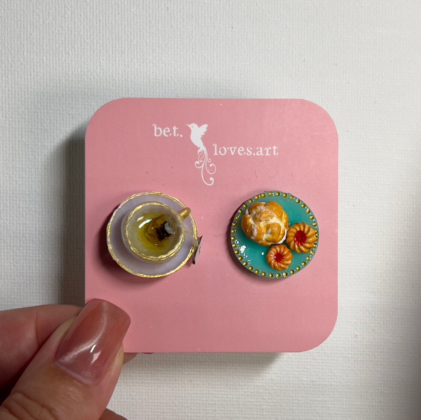 001 - Mini white teacup with tea bag, cream puff and two cookies on teal saucer