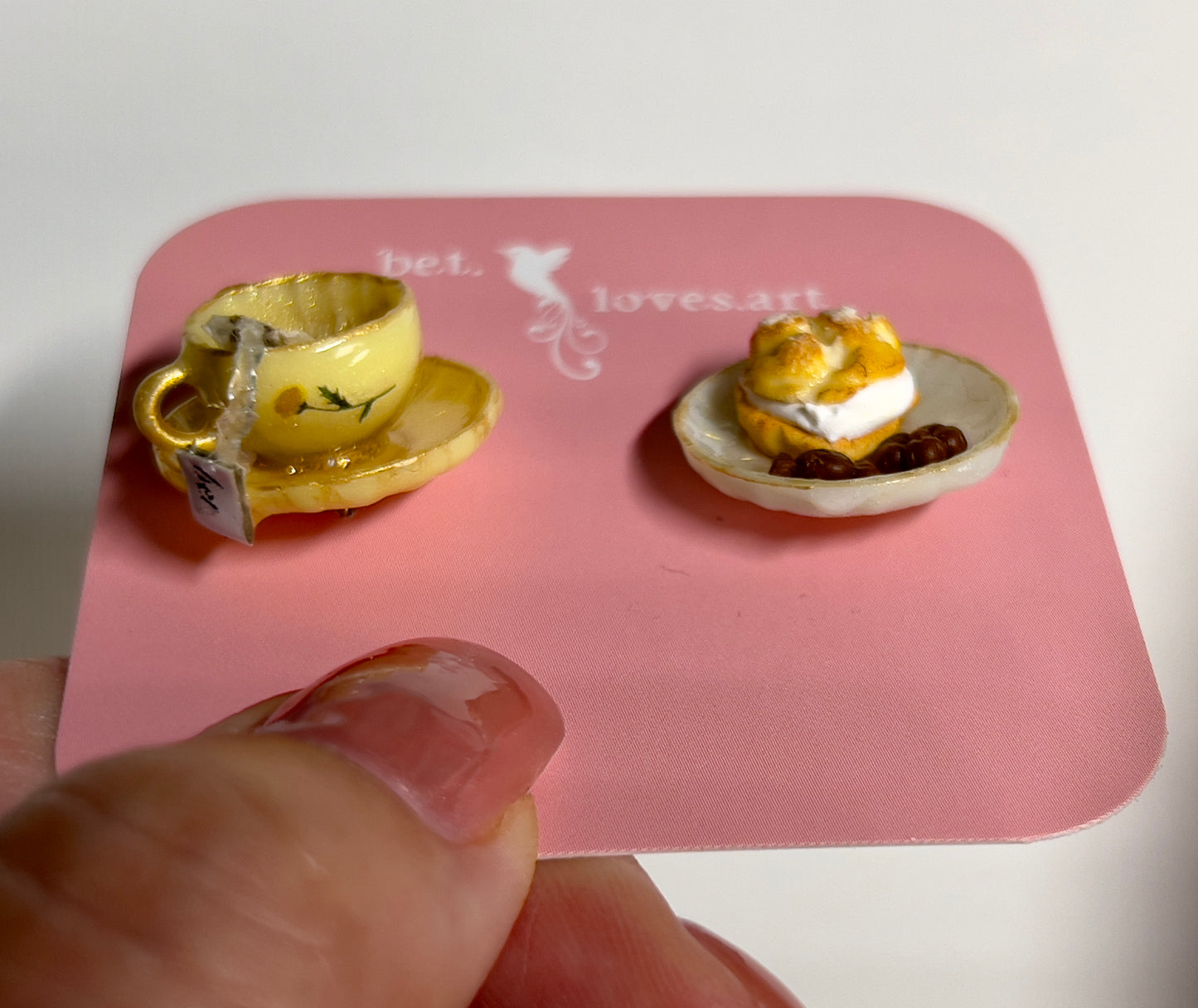 003 - Mini yellow teacup with tea bag, cream puff and chocolates on white saucer