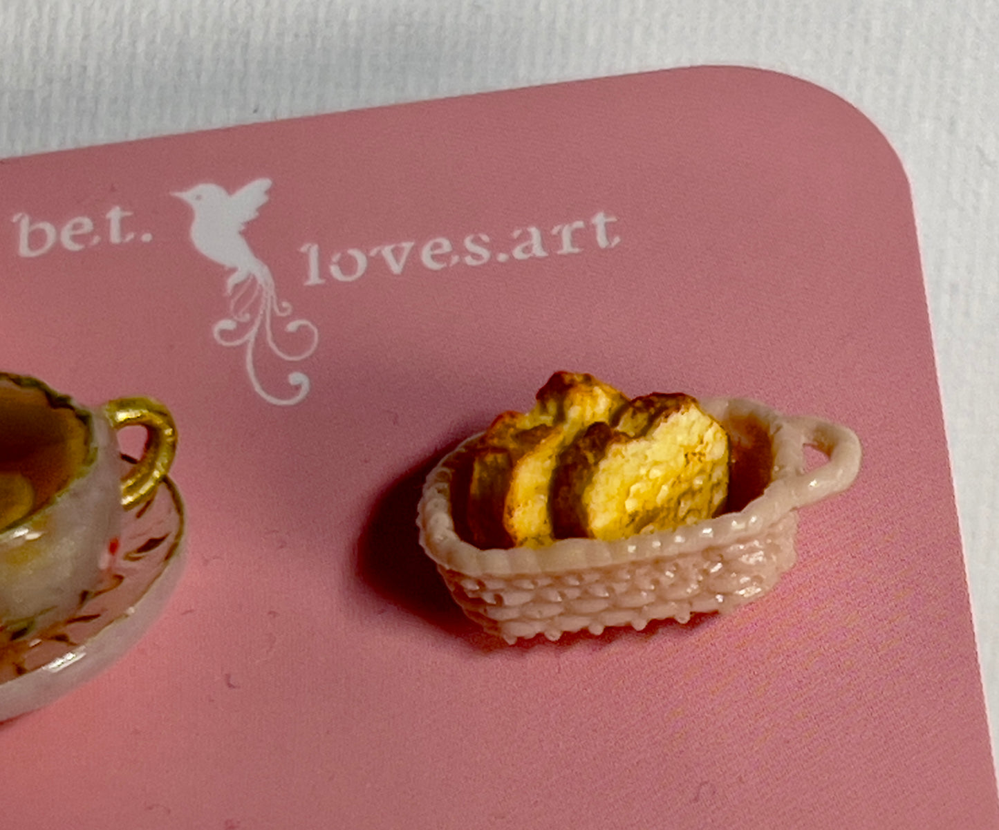 019 - Mini white opaque teacup and a basket of toasts