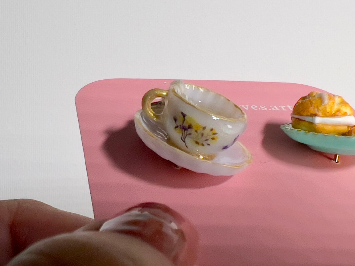 001 - Mini white teacup with tea bag, cream puff and two cookies on teal saucer