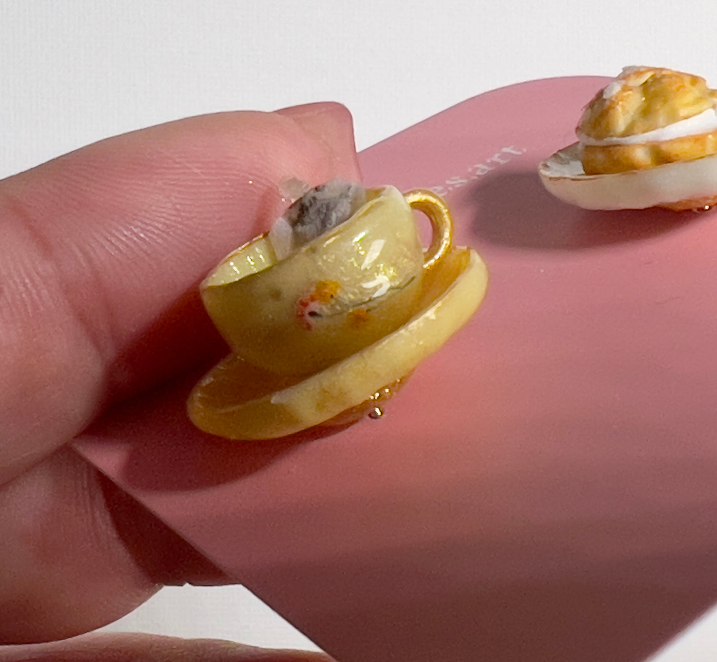 003 - Mini yellow teacup with tea bag, cream puff and chocolates on white saucer