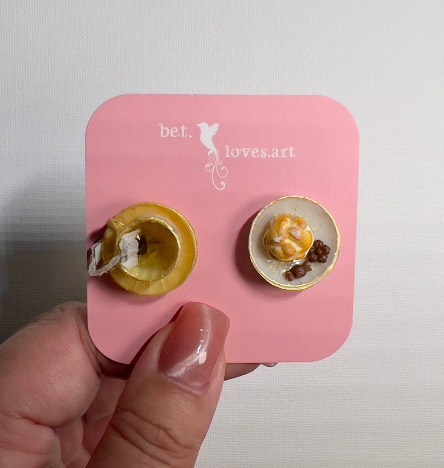 003 - Mini yellow teacup with tea bag, cream puff and chocolates on white saucer