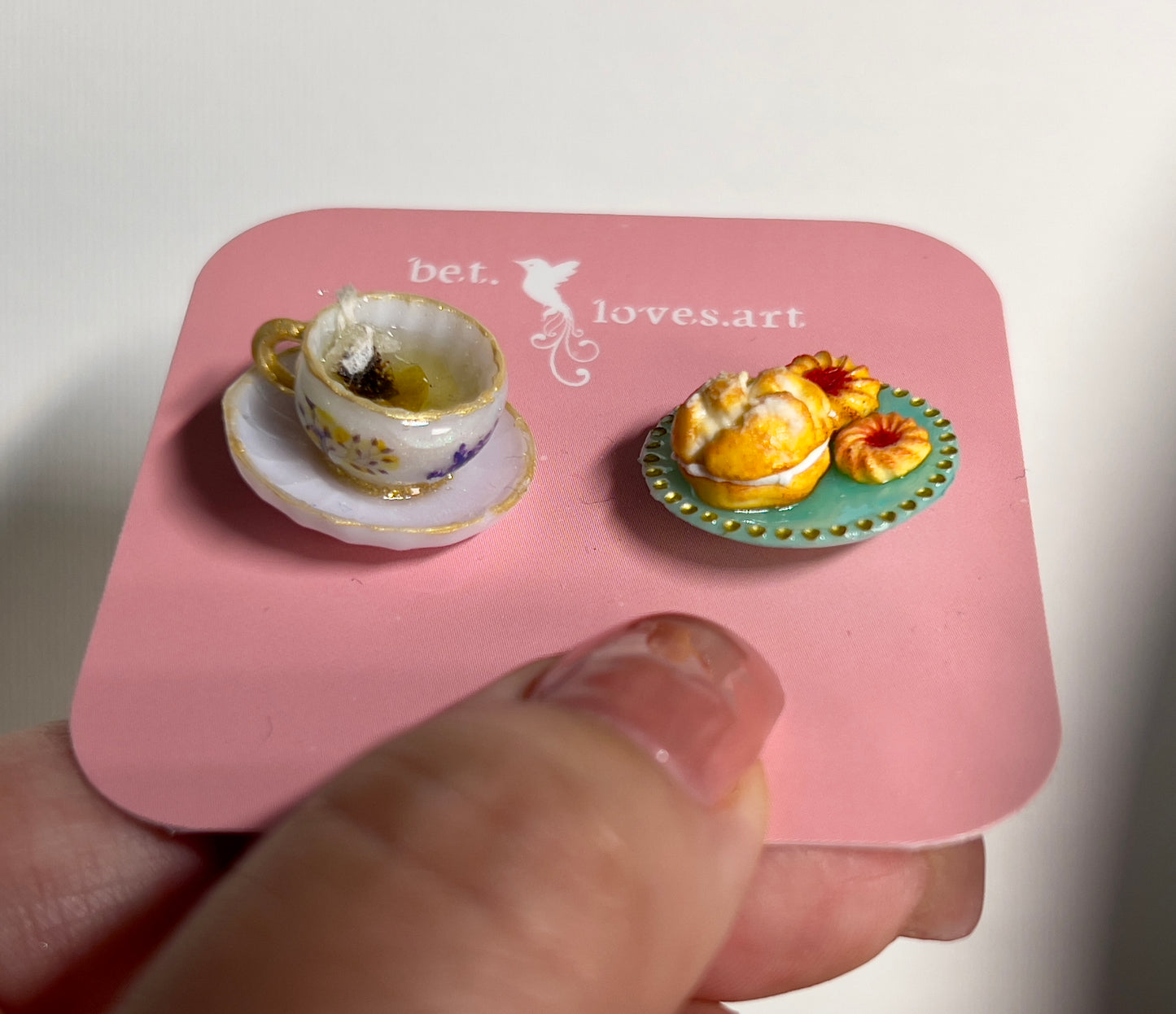 001 - Mini white teacup with tea bag, cream puff and two cookies on teal saucer