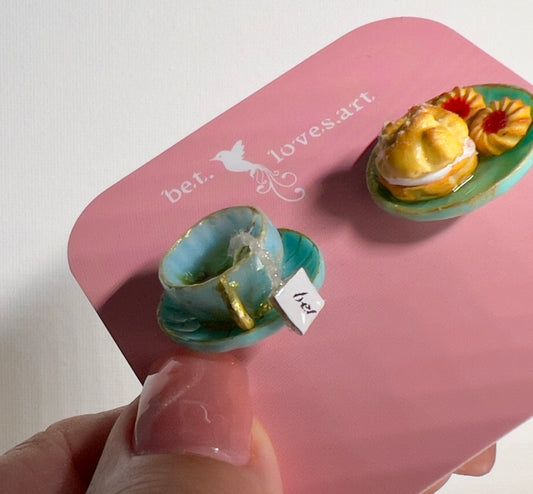 002 - Mini teal teacup with tea bag, teal saucer with cream puff and two cookies